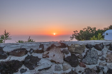 Sunset behind old rock wall of Santorini, Greece.