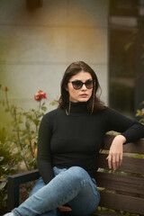 Fototapeta premium A gorgeous brunette woman wears sunglasses with sunglasses chains. Confident girl in urban portrait.