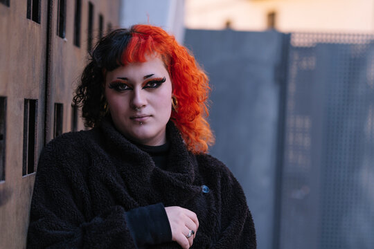 Portrait of a young transgender woman with dyed orange hair.