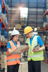 Asian engineer in helmets order and checking goods and supplies on shelves with goods background in warehouse.logistic and business export ,Warehouse worker checking packages on shelf in a large store
