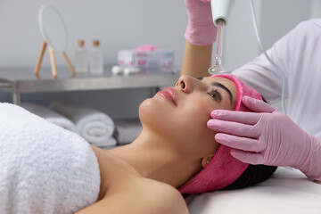 Obraz na płótnie Canvas Young woman undergoing face rejuvenation procedure with darsonval in salon
