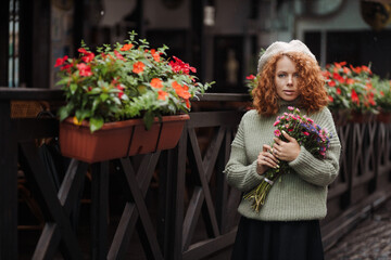 Woman portrait in a beret sweater holding a bouquet of flowers of the restaurant background 