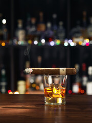 close up view of glass of burbon with cigar on top on color back.  - 549383482