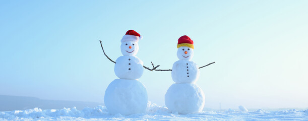 Couple of two snowman holding hands outdoors. Snowman on the snow outdoor background. Christmas banner with snowman. New year greeting card with with snowman.