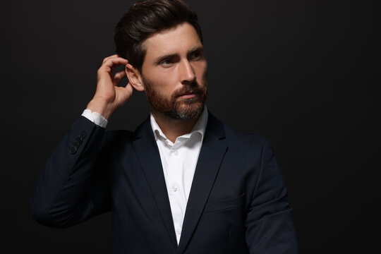 Portrait of handsome bearded man looking away on black background. Space for text