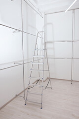 Ladder and metal pipes in empty renovated room