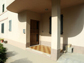 Beautiful beige building with wooden entrance door on sunny day