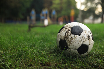 Fototapeta premium Dirty leather soccer ball on grass outdoors, space for text