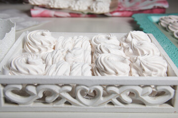 Homemade zephyr. White tray with marshmallows. Stands on black pine boards.