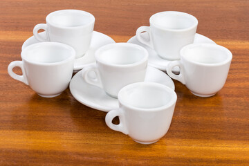 Small empty white coffee cups and saucers on wooden surface