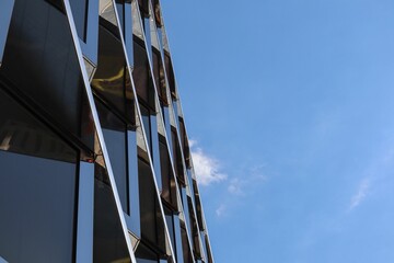 Lage hoek van een modern glazen gebouw onder een blauwe lucht in Berlijn, Duitsland.