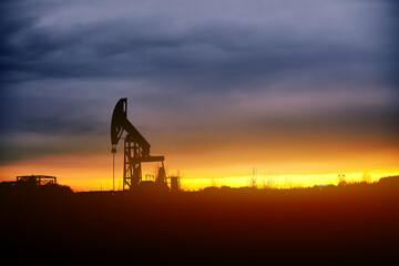 Pumpjacks. Oil pumps silhouette on a sunset sky. Oil and gas production. Oil pumps, nodding donkey or pump jack and rig against blue cloudy sky.