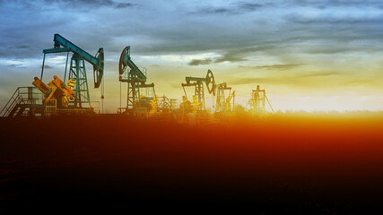 Oil pumps at sunset, industrial oil pumps equipment. Sunset and darkness. Oil field in the fog....