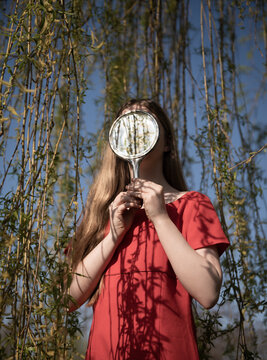 abstract fine art portrait of woman in the park holding hand mirror hiding her face