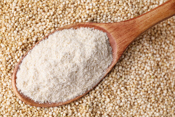 Wooden spoon with quinoa flour on seeds, closeup
