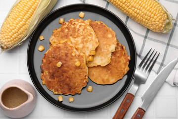Tasty corn pancakes served on white tiled table, flat lay
