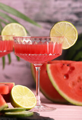 Cocktail glass of delicious fresh watermelon juice with lime on light wooden table