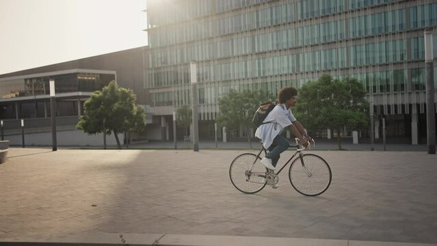  Young African American professional man going to the office by bicycle - Sustainable transport inn the city 
