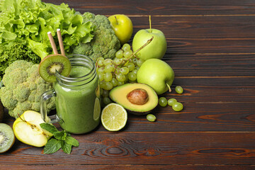 Green smoothie in mason jar and fresh ingredients on wooden table. Space for text