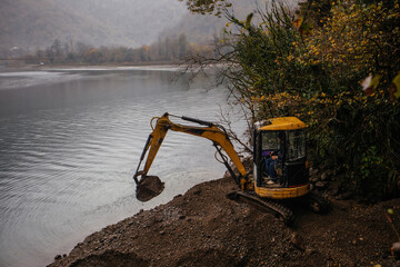 Fototapeta na wymiar Light excavator at earthmoving works on the lake