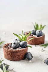 Chocolate brownies decorated with blueberries and rosemary on white textured background close up. Christmas, New Year recipe concept, menu. Text space