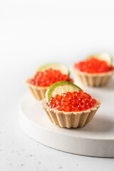 Festive New Year appetizer tartlets stuffed with red caviar and a slice of lime close up on a white tray with copy space. Christmas or new year food recipe