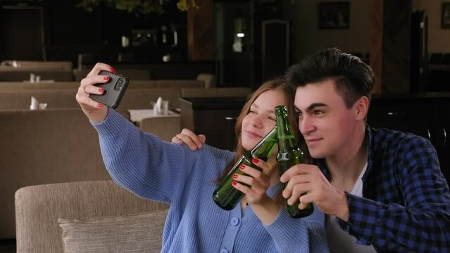 A couple in love is relaxing in a cafe with beer and pizza, they take selfies on their phone. A group of friends relax in a pizzeria, they drink beer and take photos on the phone.