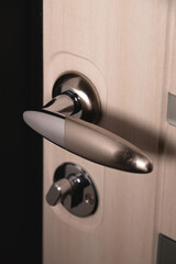 Close up of stylish silver chrome door handle on modern interior door. Stylish light brown door with frosted glass inserts. Concept of catalog of door handles for furniture store