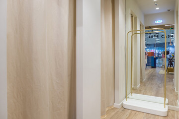 Fitting rooms in a women's clothing store with a large mirror.