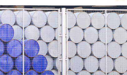 Group of blue and white 200 liter oil drum stacking behind mesh fence inside of industrial factory...