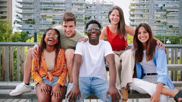 Happy multiracial young people smiling together looking at camera, Five teenage friends having fun and laughing taking picture outside on city street. Lifestyle Concept. High quality 4k slowmotion