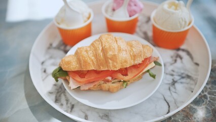 Ice cream and croissant with meat on the plate at the cafe.
