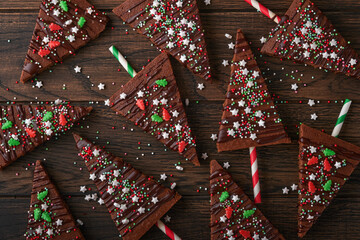Chocolate brownies Christmas tree with chocolate icing and festive sprinkles on wooden table....