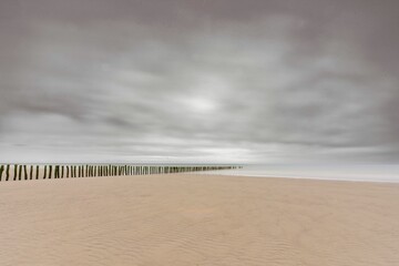 Long exposure shot of the breakwater in the North Sea, France, in cloudy sky background