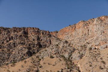 View of a steep rocky valley with blue sky.