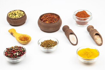 Spices in glass and wooden bowls isolated on a white background.