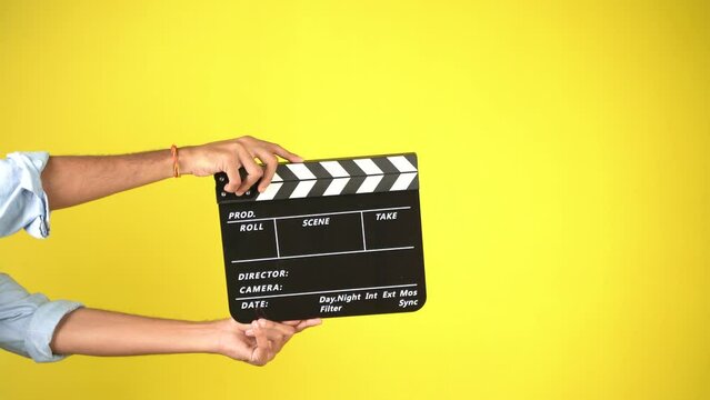 Hand is holding clapper board or clapperboard or movie slate, used in film production and cinema ,movies industry isolated over color background.