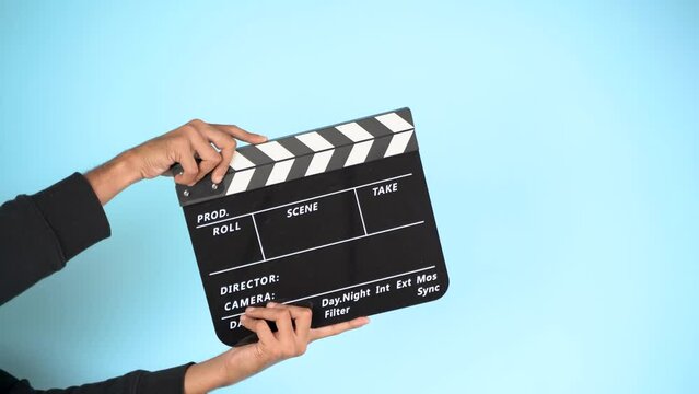 Hand is holding clapper board or clapperboard or movie slate, used in film production and cinema ,movies industry isolated over color background.
