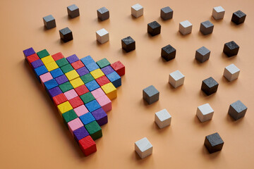 Pyramid from colorful cubes and gray and black ones around. Diversity and inclusion in society.