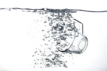 Transparent glass dropped into the water on a white background
