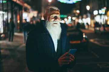 Happy senior hipster man using mobile phone outdoor in winter night- Focus on face