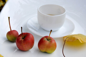 Apples on a white dish with a white cup