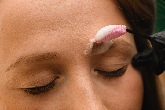 view on woman face on the eyebrows of which cleaning foam applied with brush
