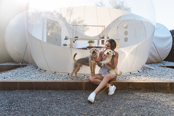 Cheerful woman petting dogs outside glamping tent