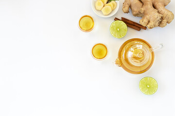 Top view of a cup of tea with ginger root, lime, cinnamon and teapot on white background. Health drink concept.. - obrazy, fototapety, plakaty