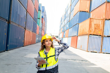 Professional worker in helmet and uniform inspecting cargo at freight container shipping company before being exported to the port.