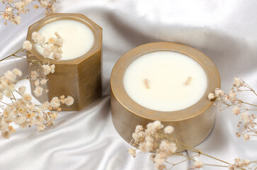 Scented candles in a pot. Soy wax candles on a background of white fabric and gypsophila