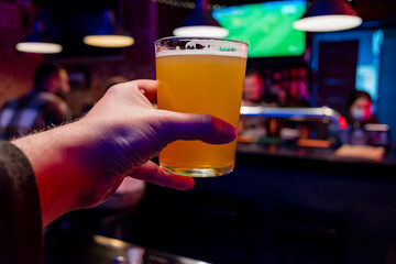 man holds a glass of beer in his hand at the bar or pub