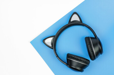 Black wireless headphones on a white-blue background, copy space