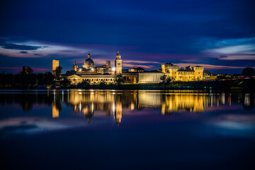 Obraz premium Panoramic evening view of Mantua, Lombardy, Italy; scenic twilight skyline view of the medieval town reflected in the lake waters